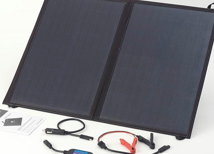 Portable fold-up solar panel powering campervan battery at campsite
