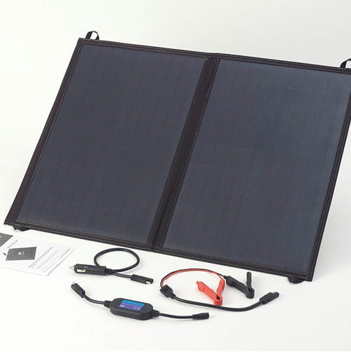 Portable fold-up solar panel powering campervan battery at campsite